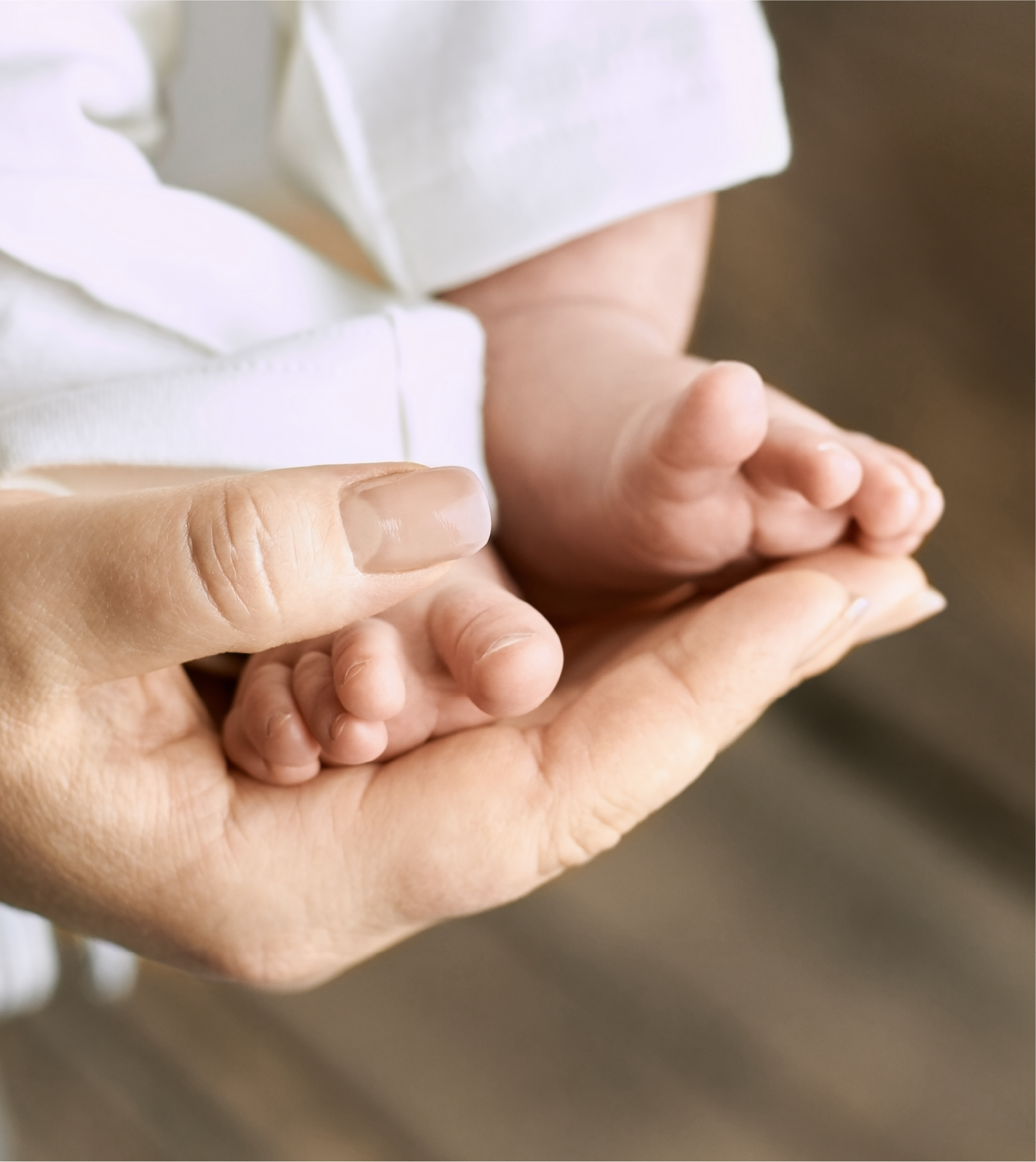 Close-up of a baby's feet being held by an adult hand with a blurred background